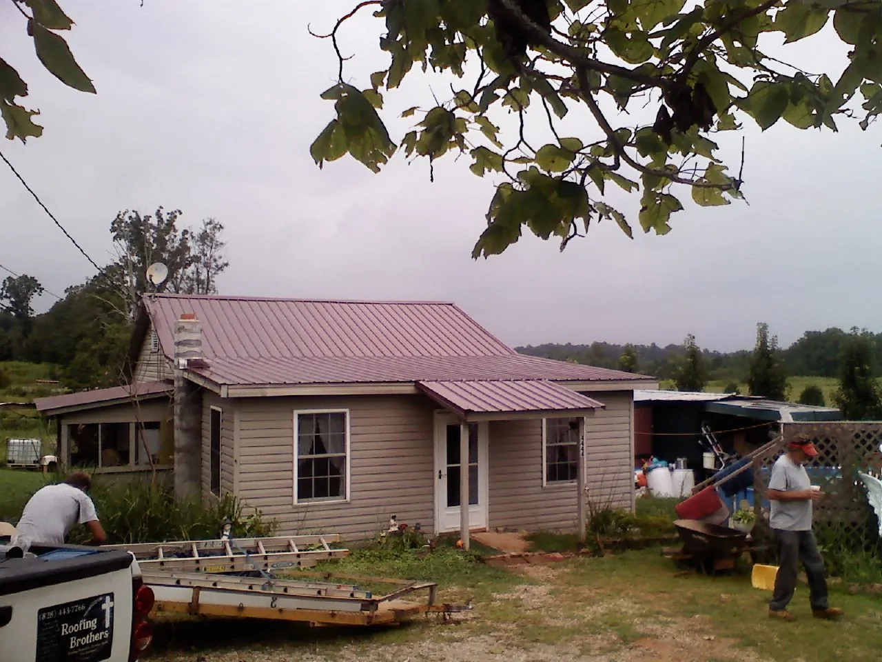 Crew finishing a mauve metal roof on a small farmhouse in Bristol